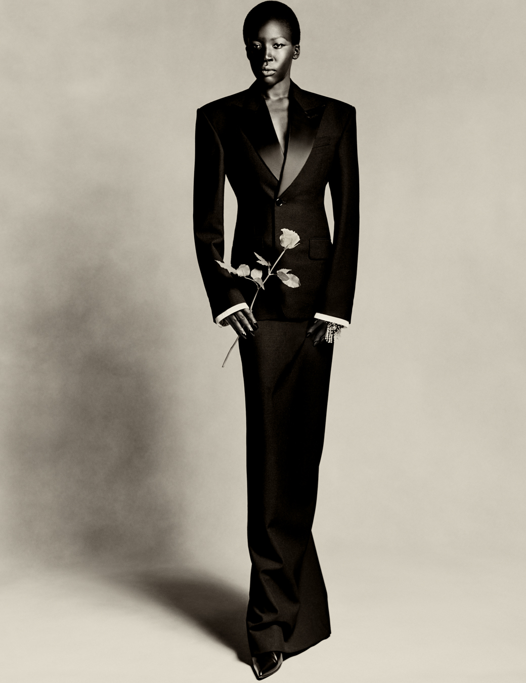 model wears a two piece suit by balenciaga and holds a rose in their hand.