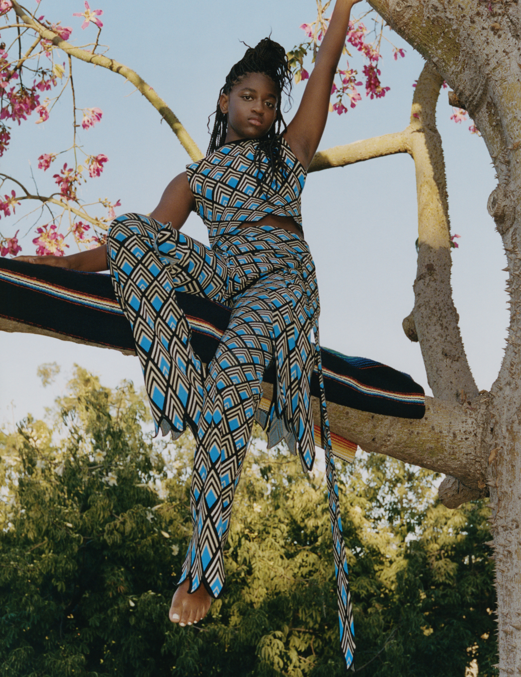 Zaya sits in a tree on a scarf wearing a patterned blue two piece