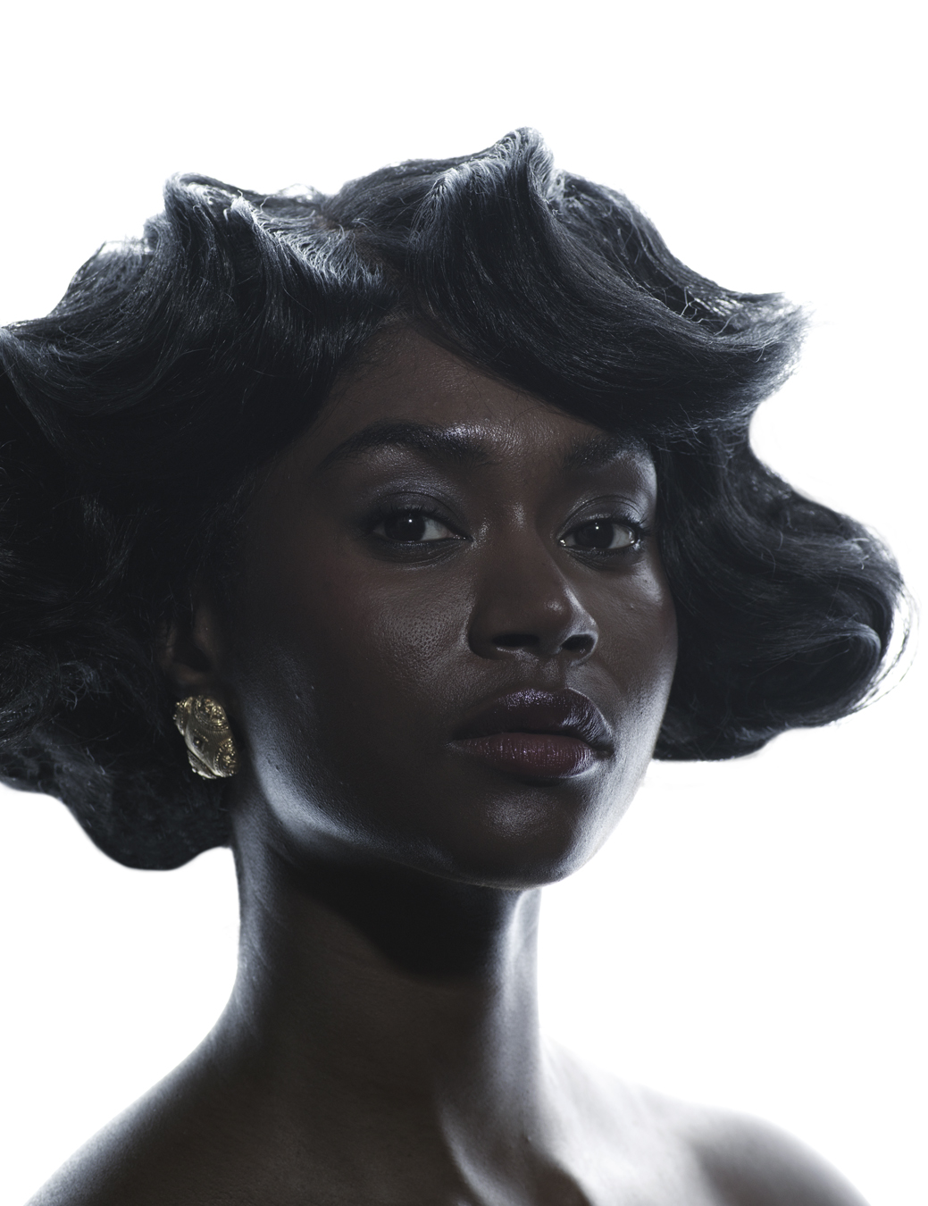 model has black short waved hair with a gold earring.