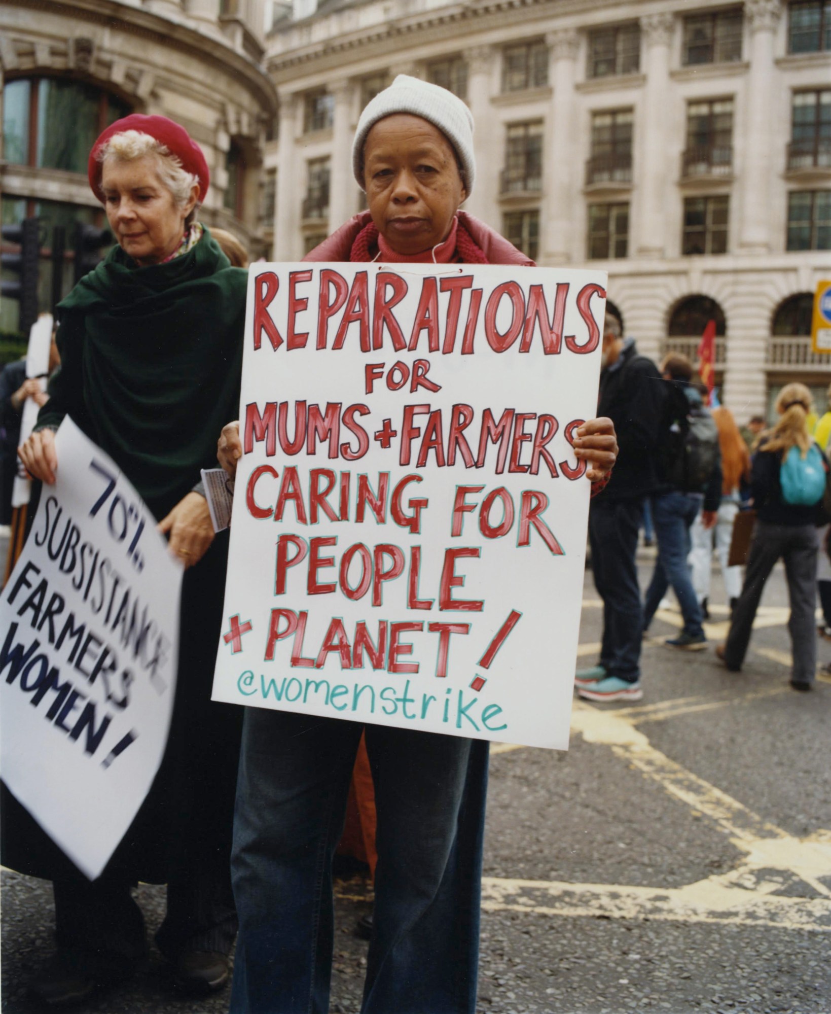 a woman holding a protest sign for climate crisis reparations by heather glazzard