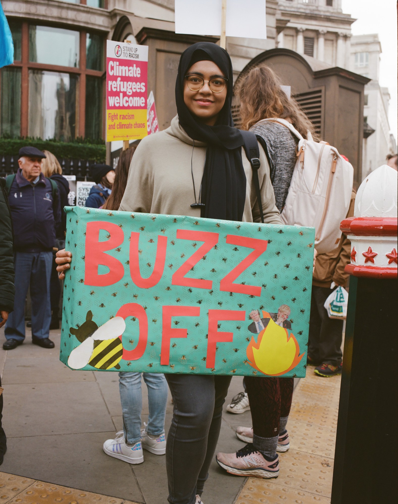 a young activist holding a sign that says buzz off at a climate protest by heather glazzard