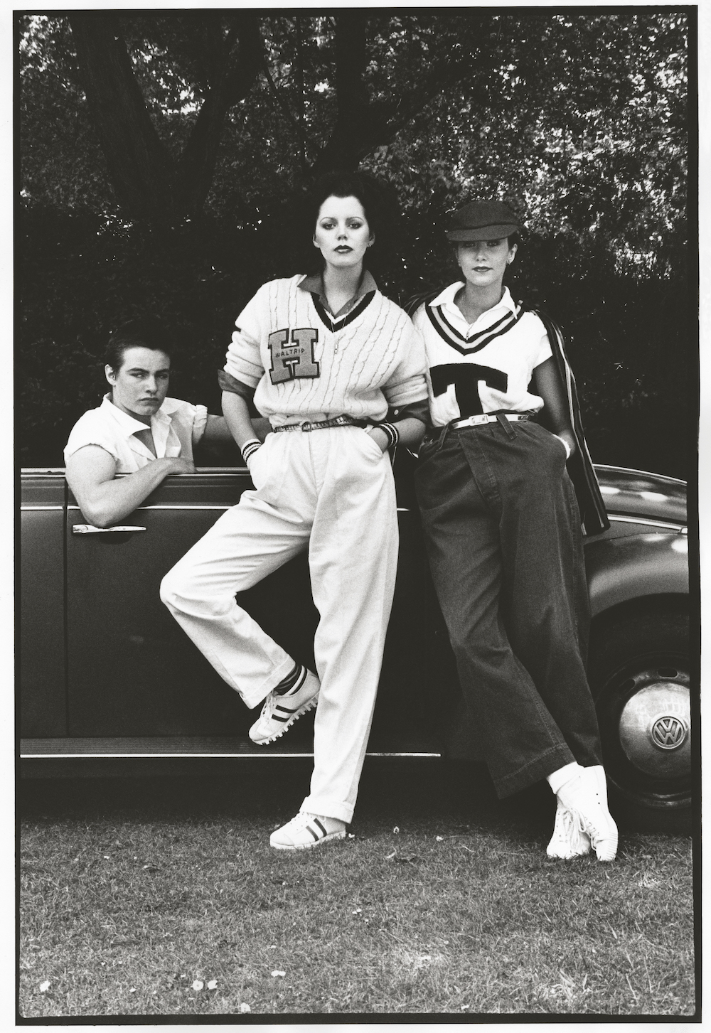 A vogue image shot by harri peccinotti of three models in american athleisure, leaning against a car, styled by caroline baker