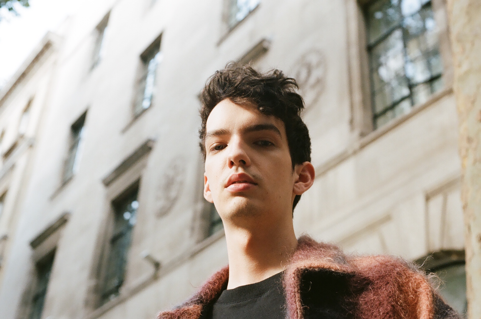 the actor kodi smit mcphee stood outside a large building in london