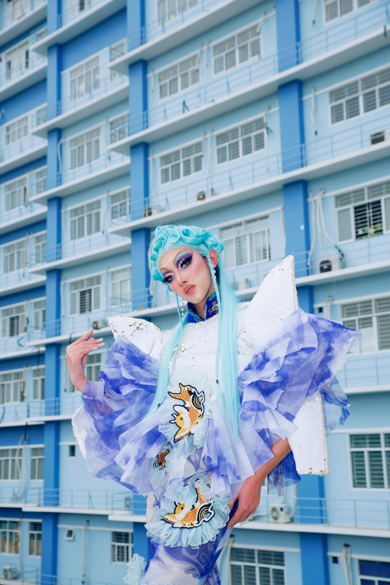 vietnamese drag queen harley posing in front of a blue building in ho chi minh city