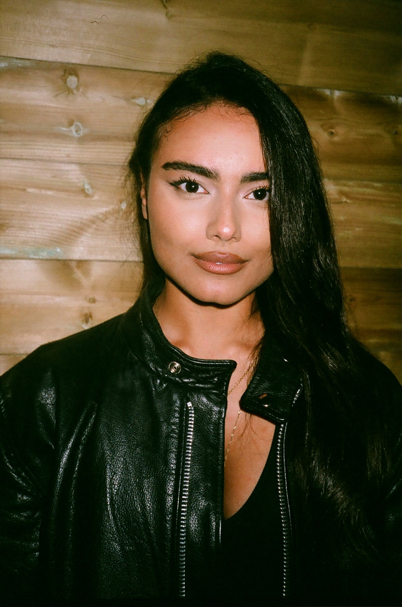 a girl in a leather jacket smiles to camera