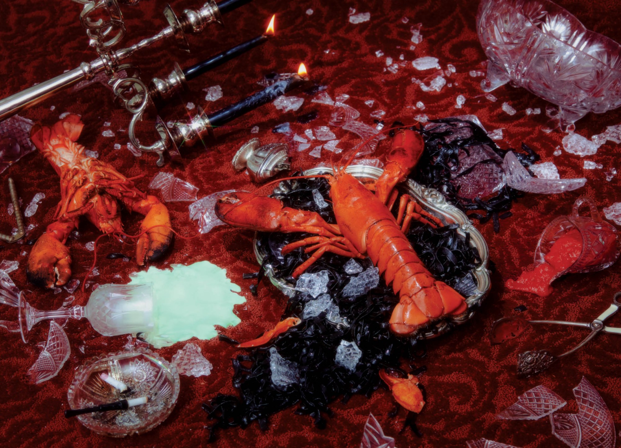 lobster and broken glassware on a red velvet tablecloth