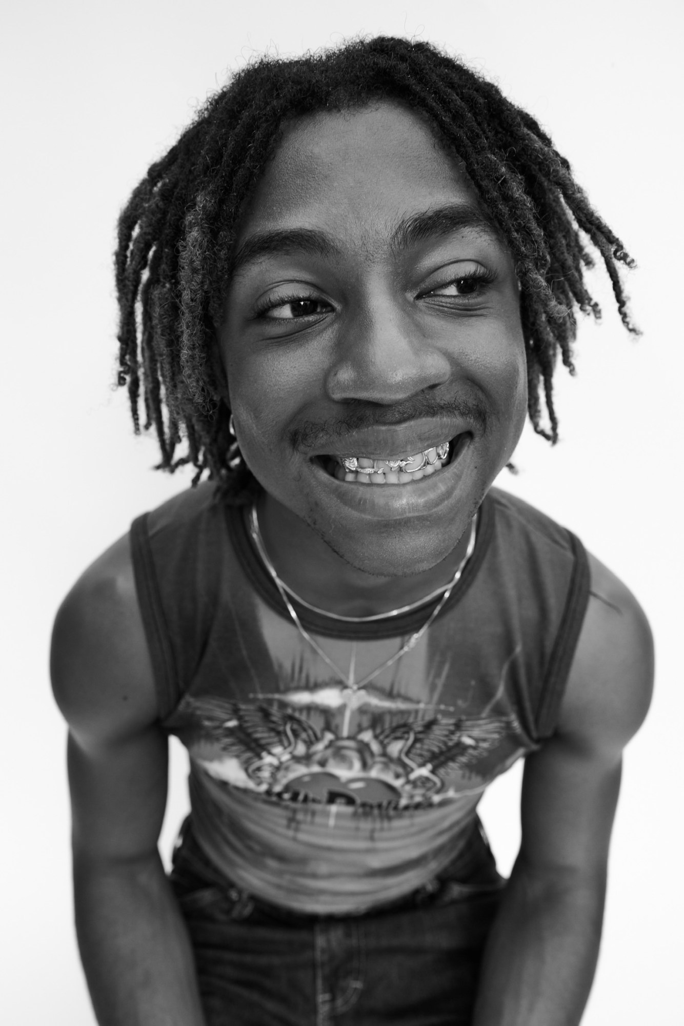 a young man in a tank top with silver grills in his teeth