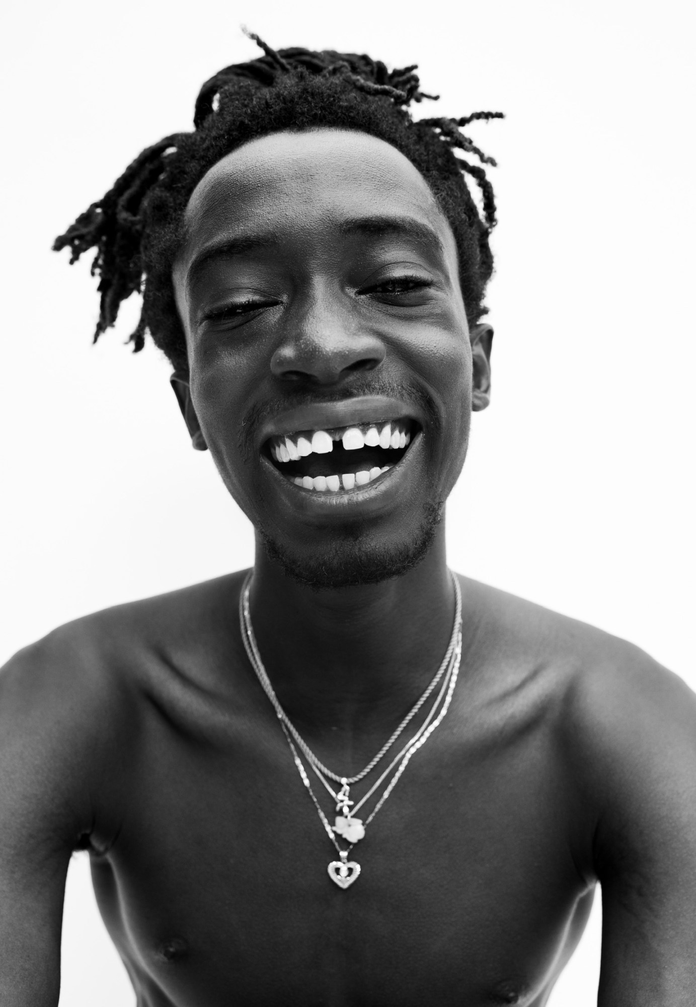 a topless young man wearing silver necklaces