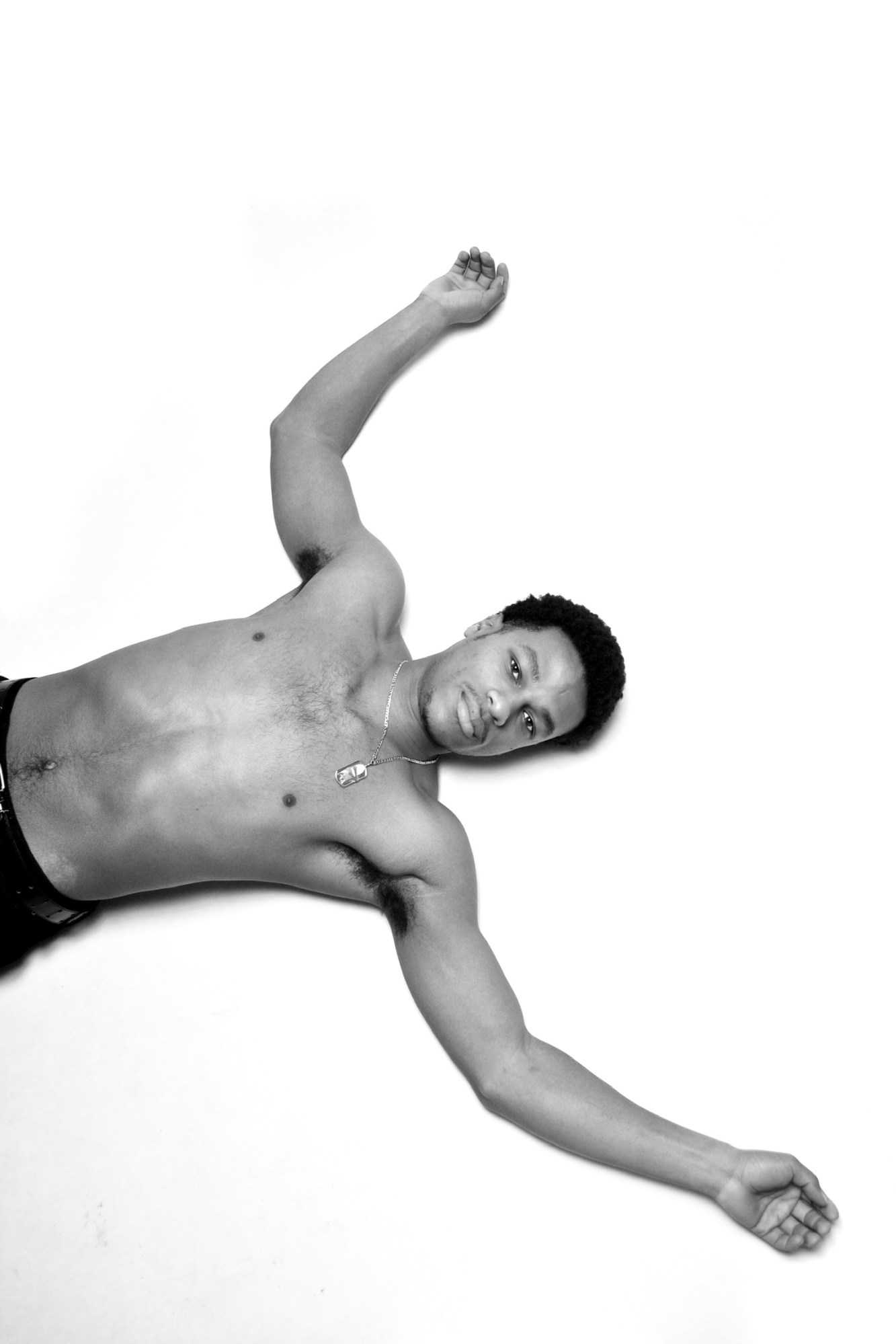 a topless young man lies on the floor of a studio looking up