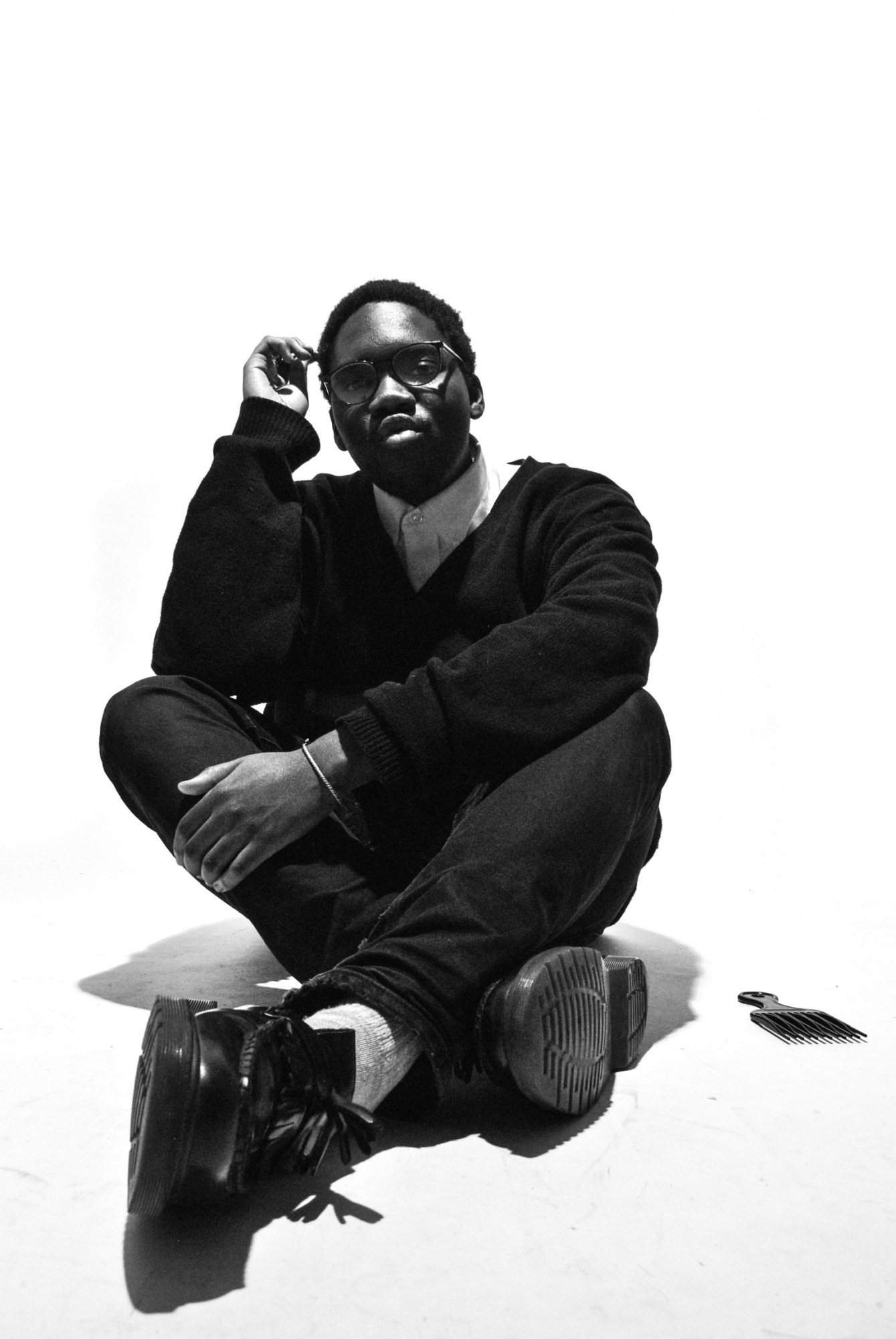 a young man sits crossed-legged on the floor of a studio