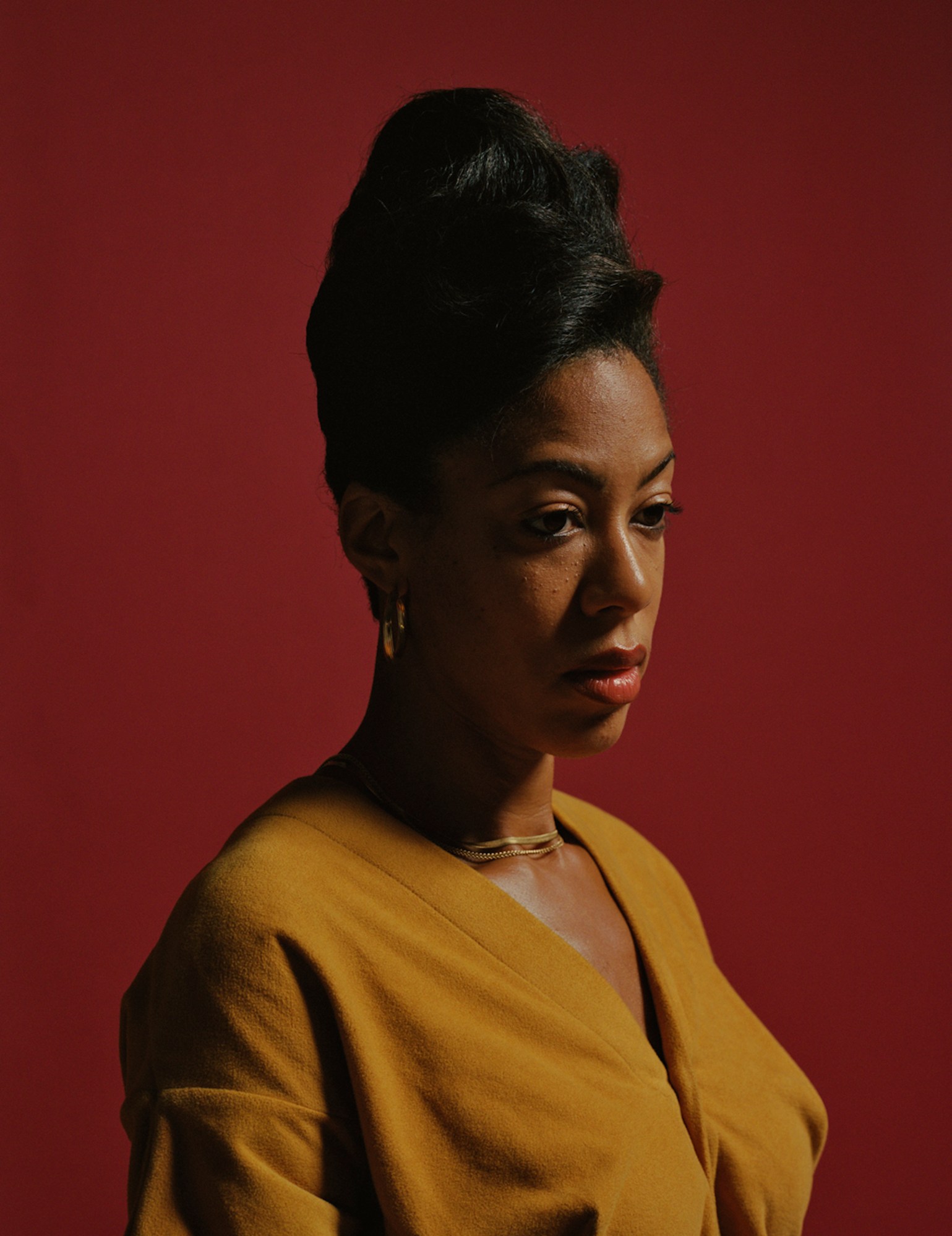 Portrait of Deana in a yellow top, gold chains, gold earrings and an up-do hair style.