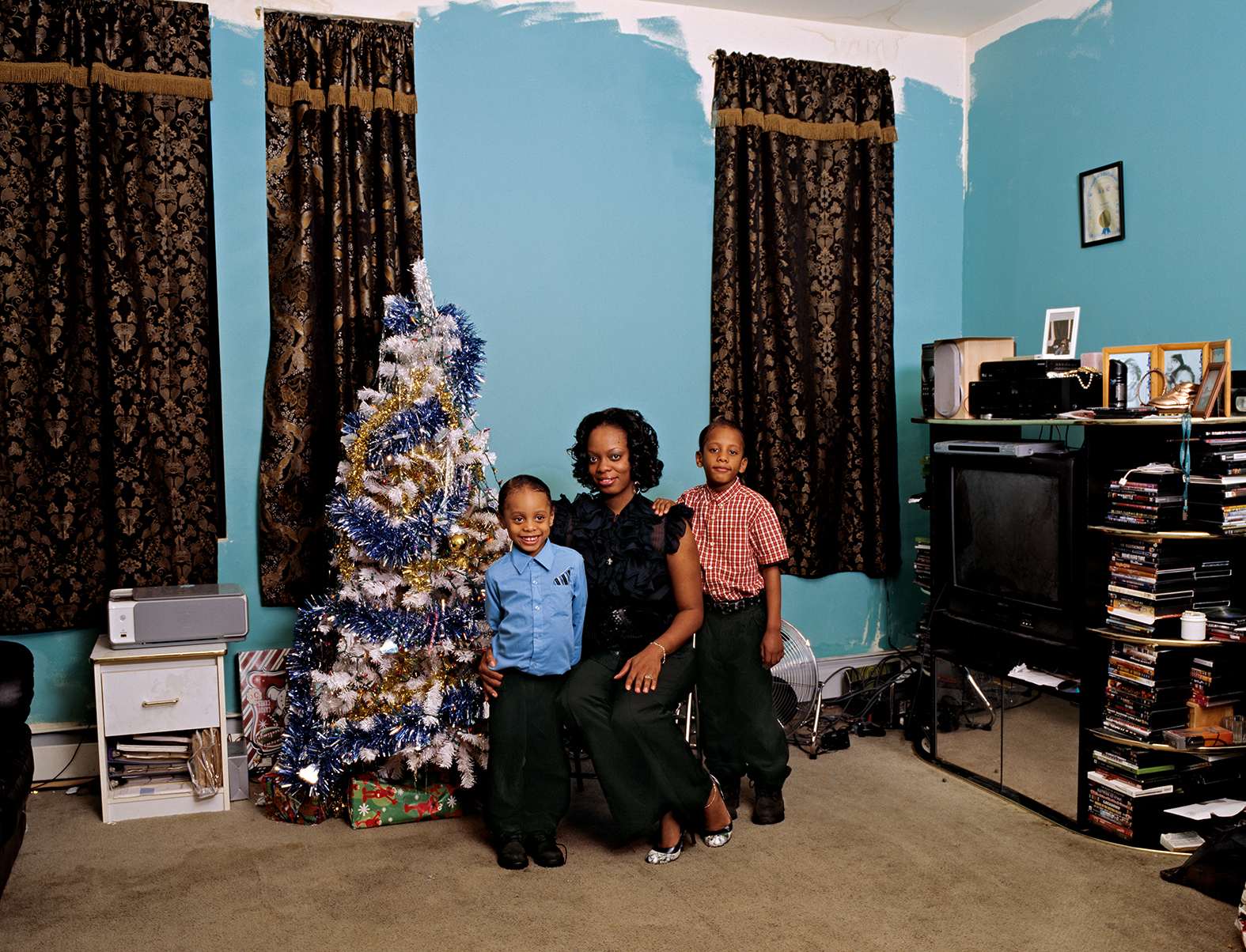 a woman and two young children sitting by a christmas tree