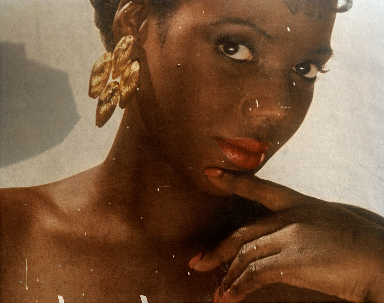 a woman with gold earrings and red lipstick