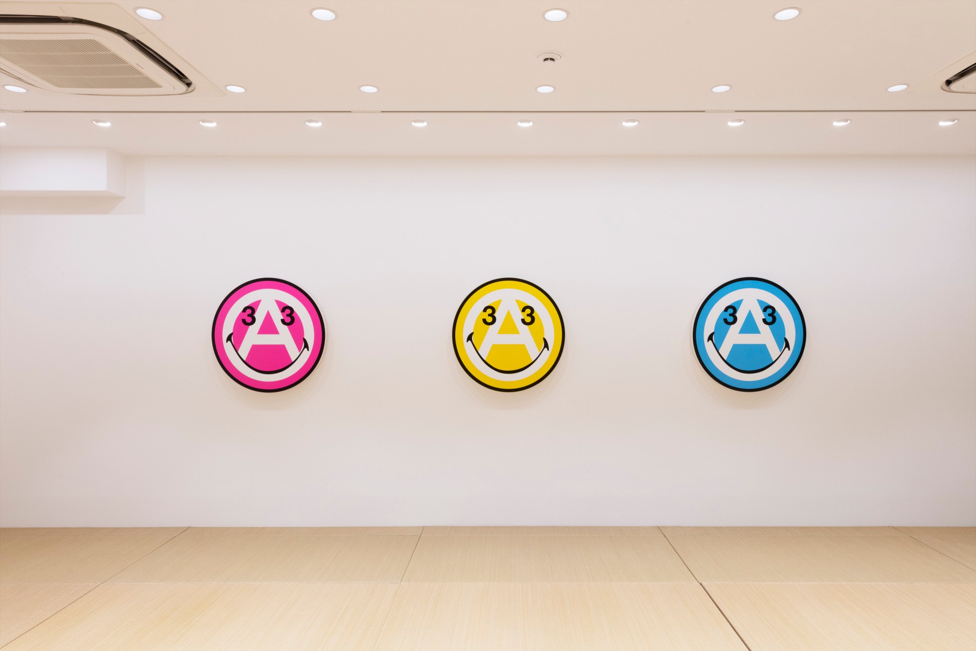 Anarchy symbol turned into a smiley face in pink, yellow and blue