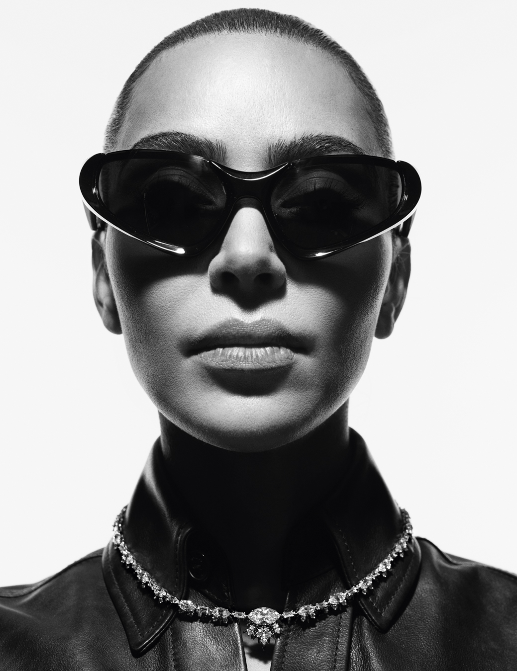 Portrait of Kim Kardashian wearing sunglasses and a leather jacket with a diamond necklace over the collar