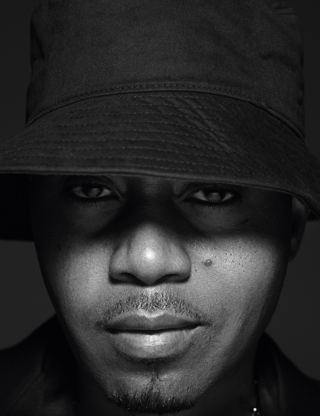 Close up of Nas's face while he wears a black bucket hat.