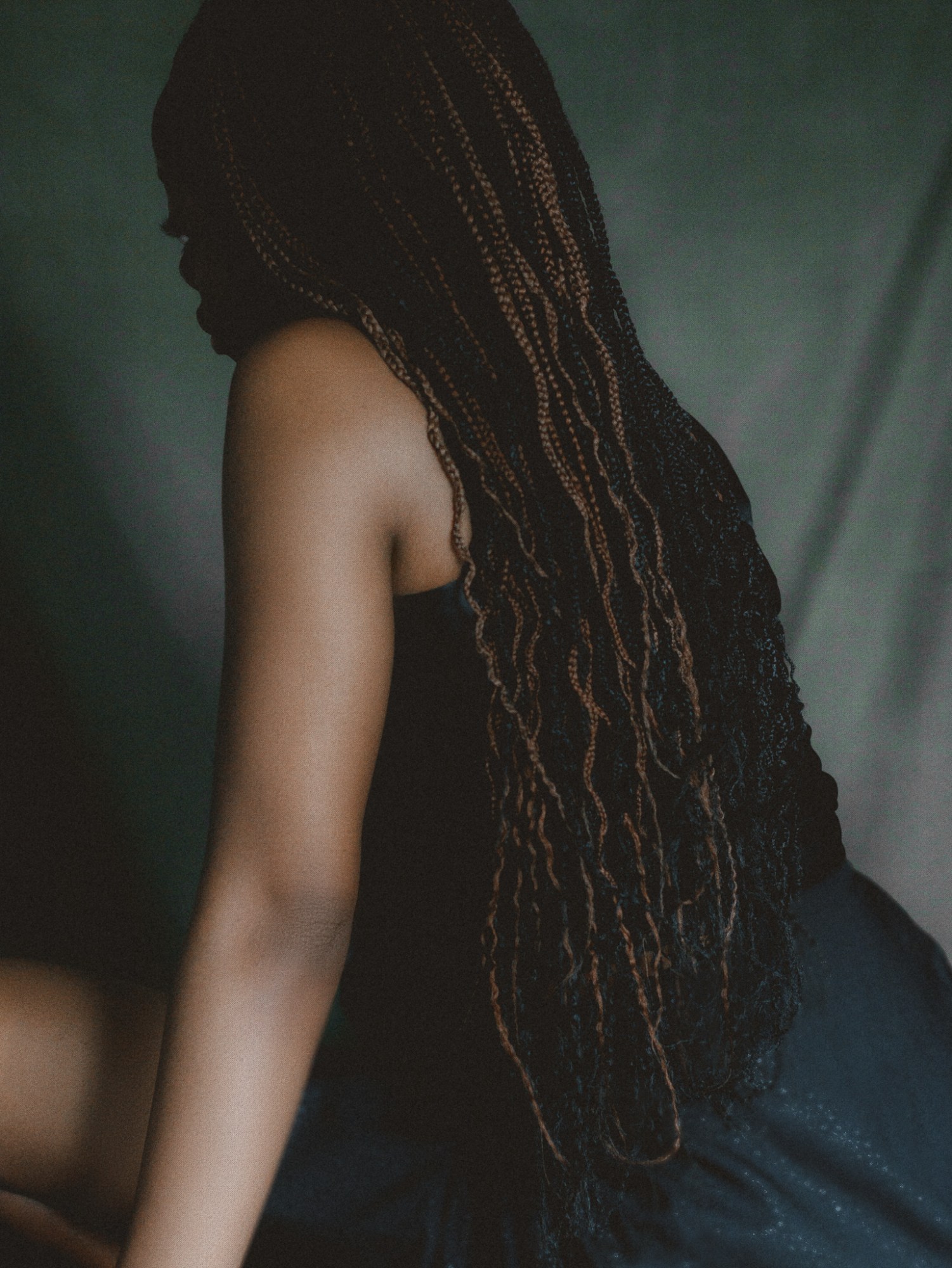 A woman with long braided hair sitting with her back to the camera