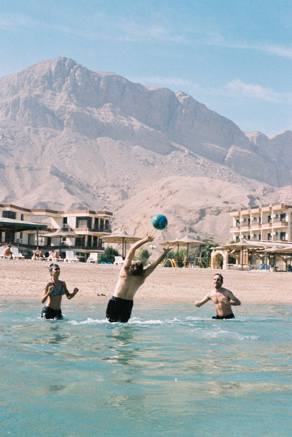 Three people play volleyball in the ocean