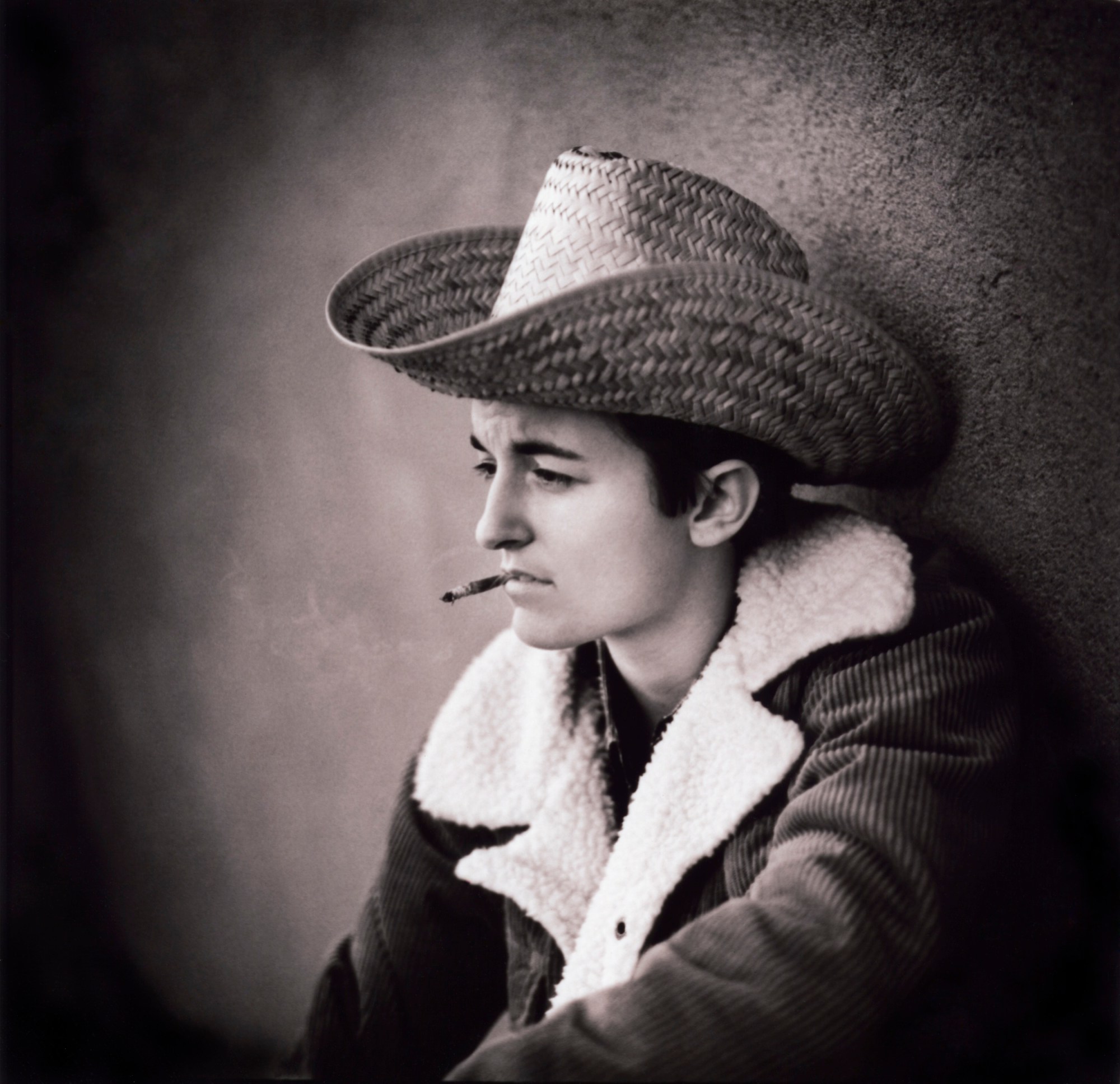 portrait of a lesbian in a cowboy hat smoking a cigarette