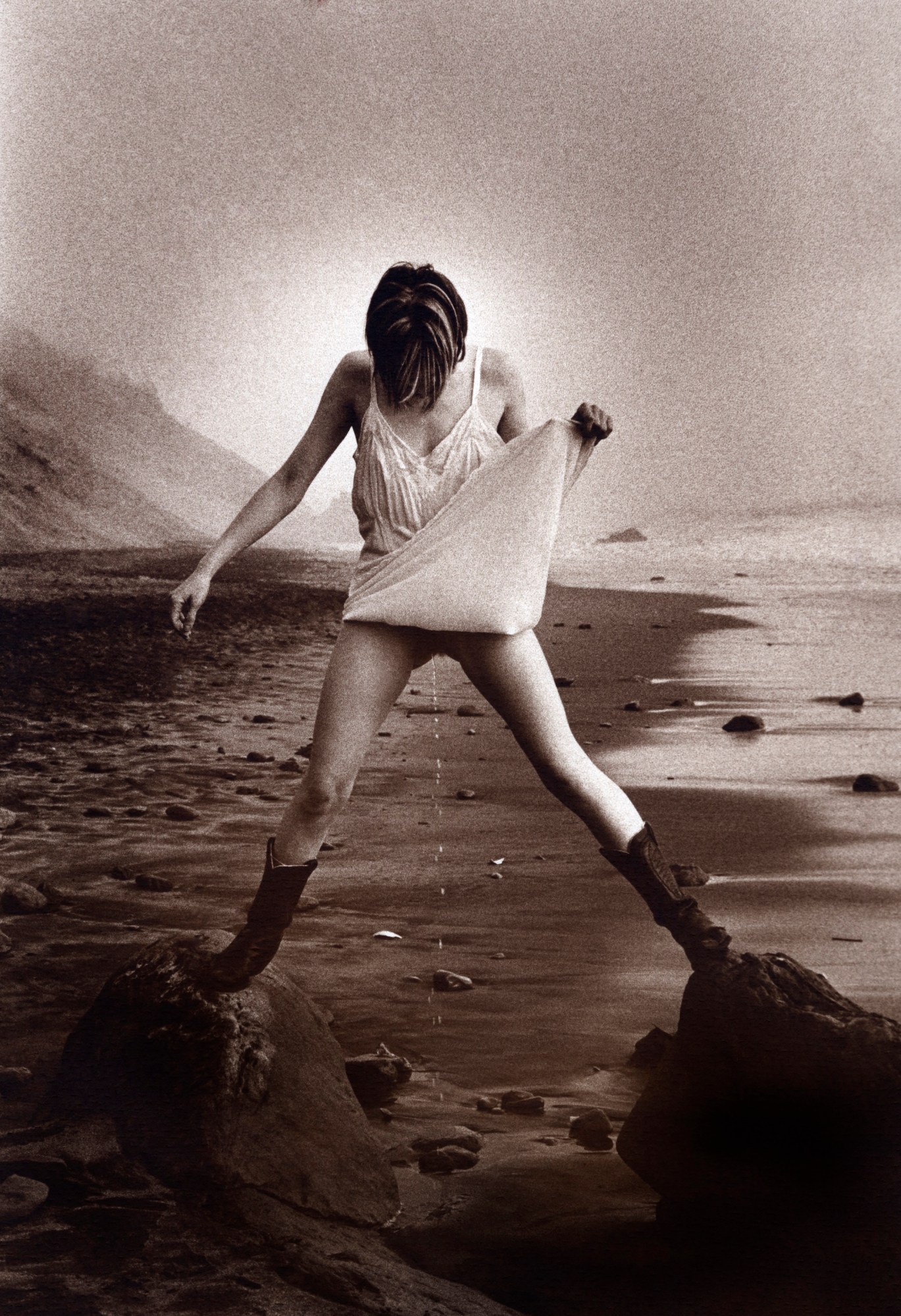 a woman holding up her dress and peeing on the beach in san francisco