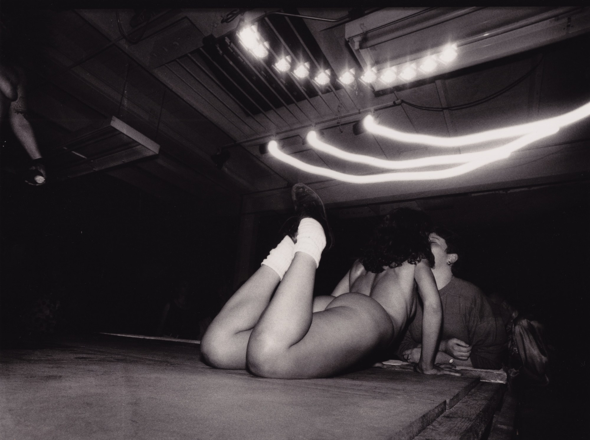 a nude dancer lying across the stage and kissing someone at a lesbian sex club in san francisco