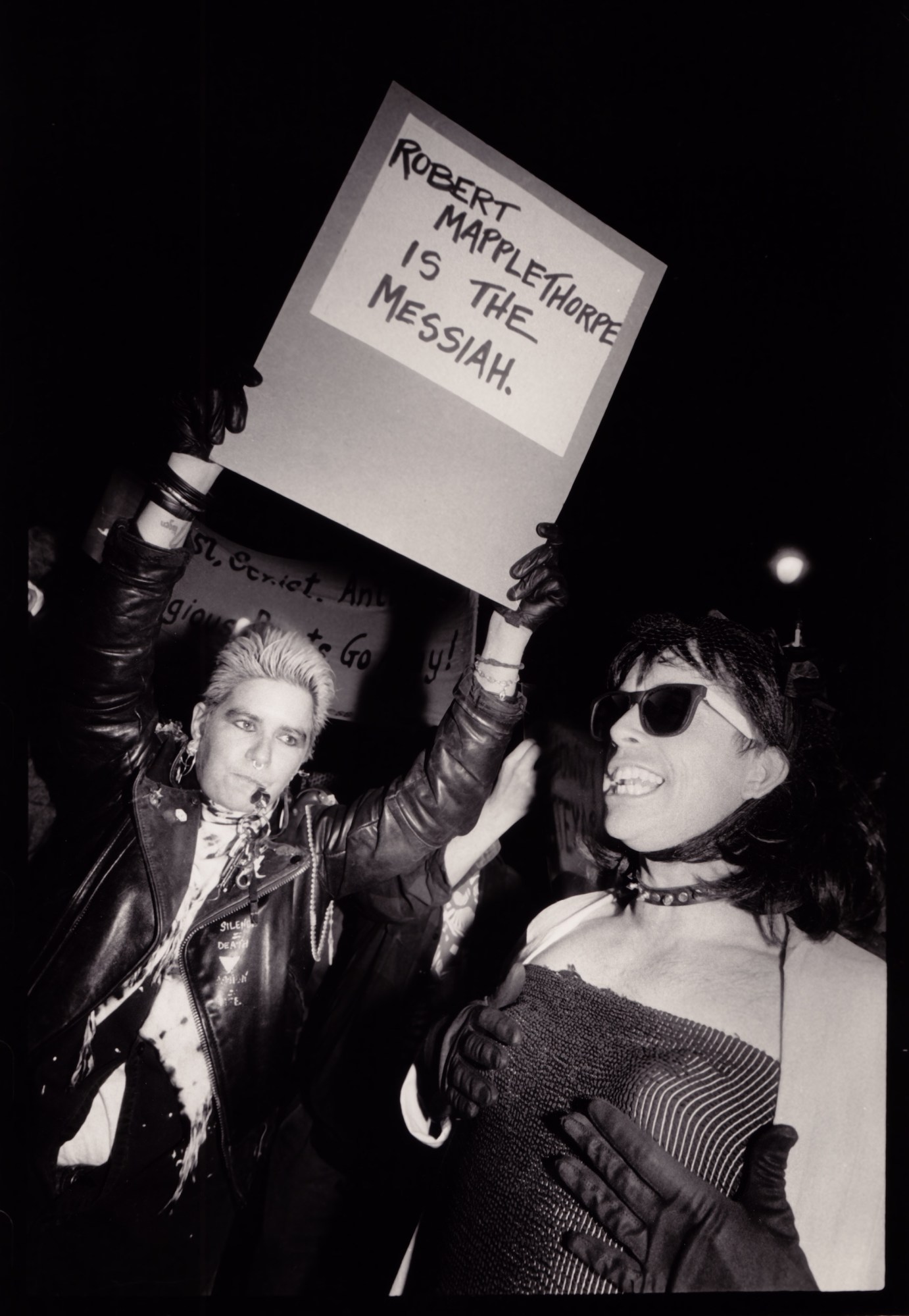 two lesbian protesters with a sign that says robert mapplethorpe is the messiah