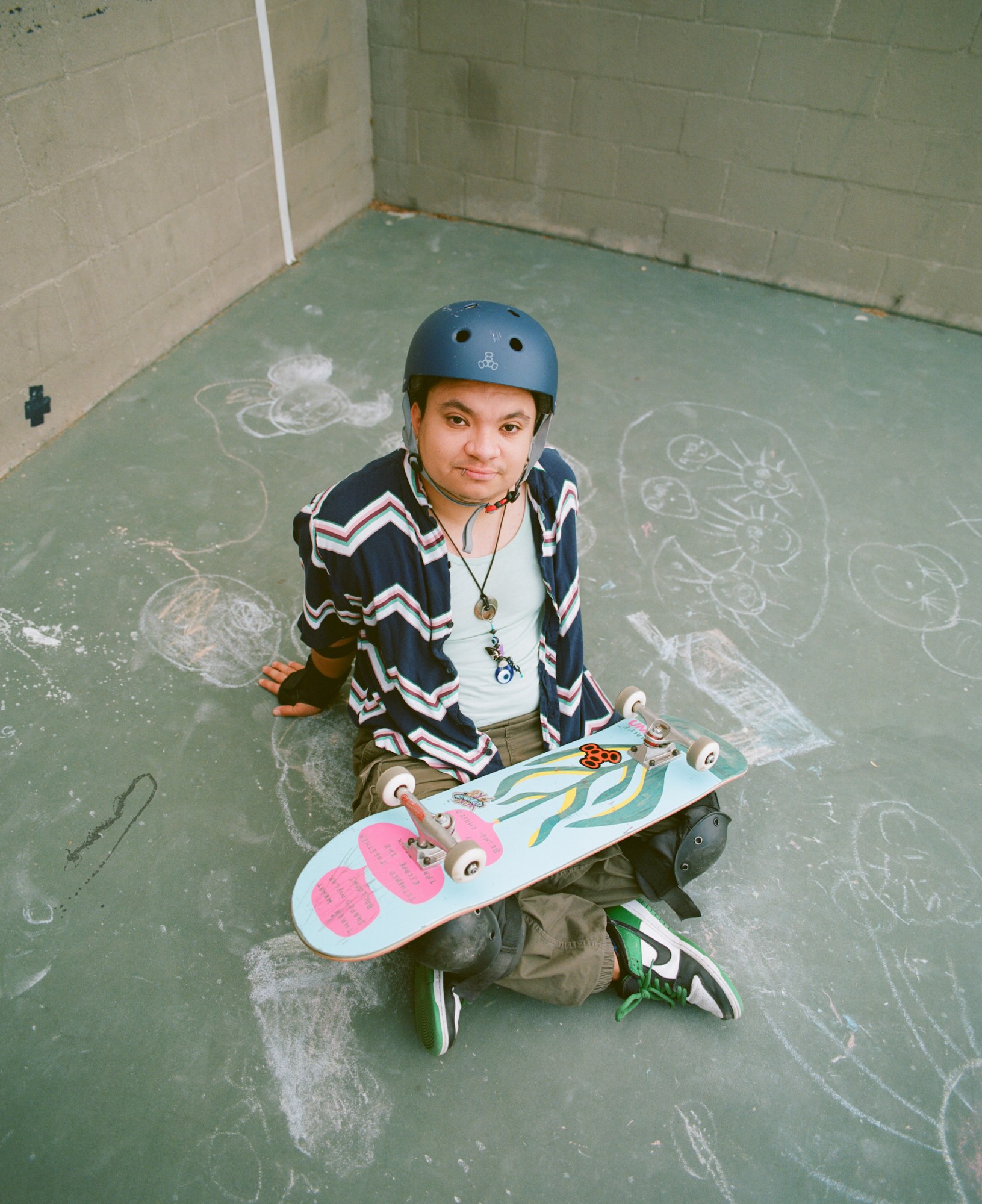 matt pasini sitting with their legs crossed and their skateboard in their lap