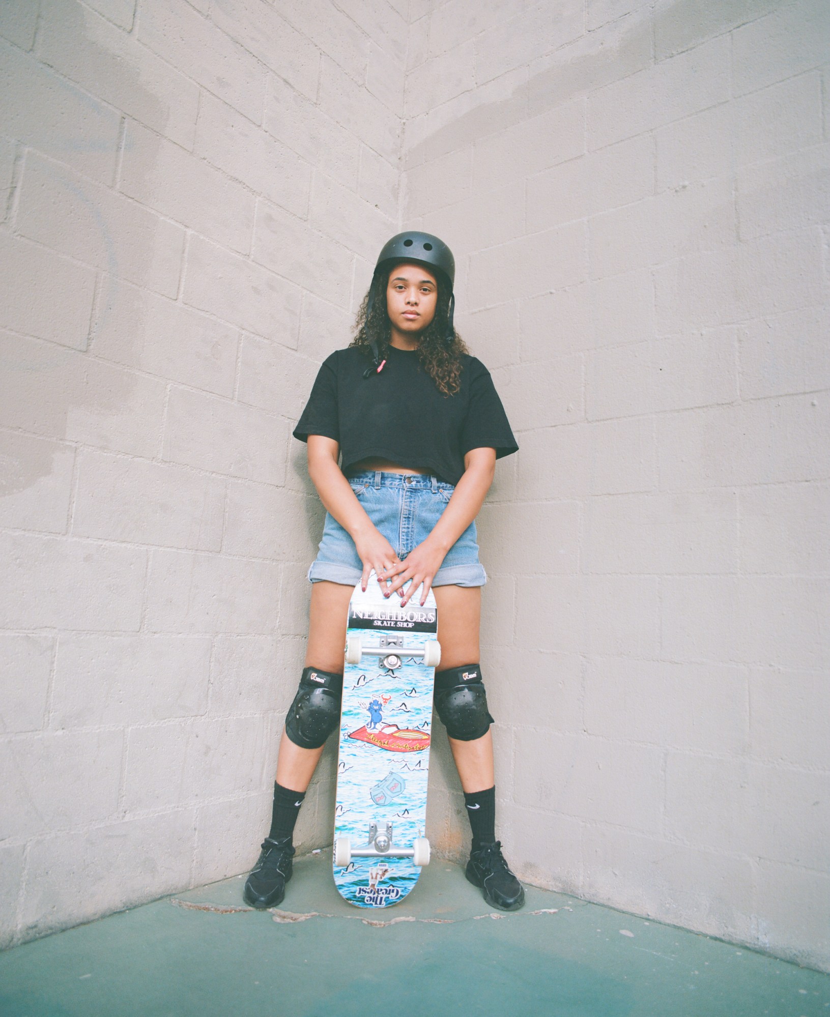 cerise castle standing in a corner with her hands on her skateboard