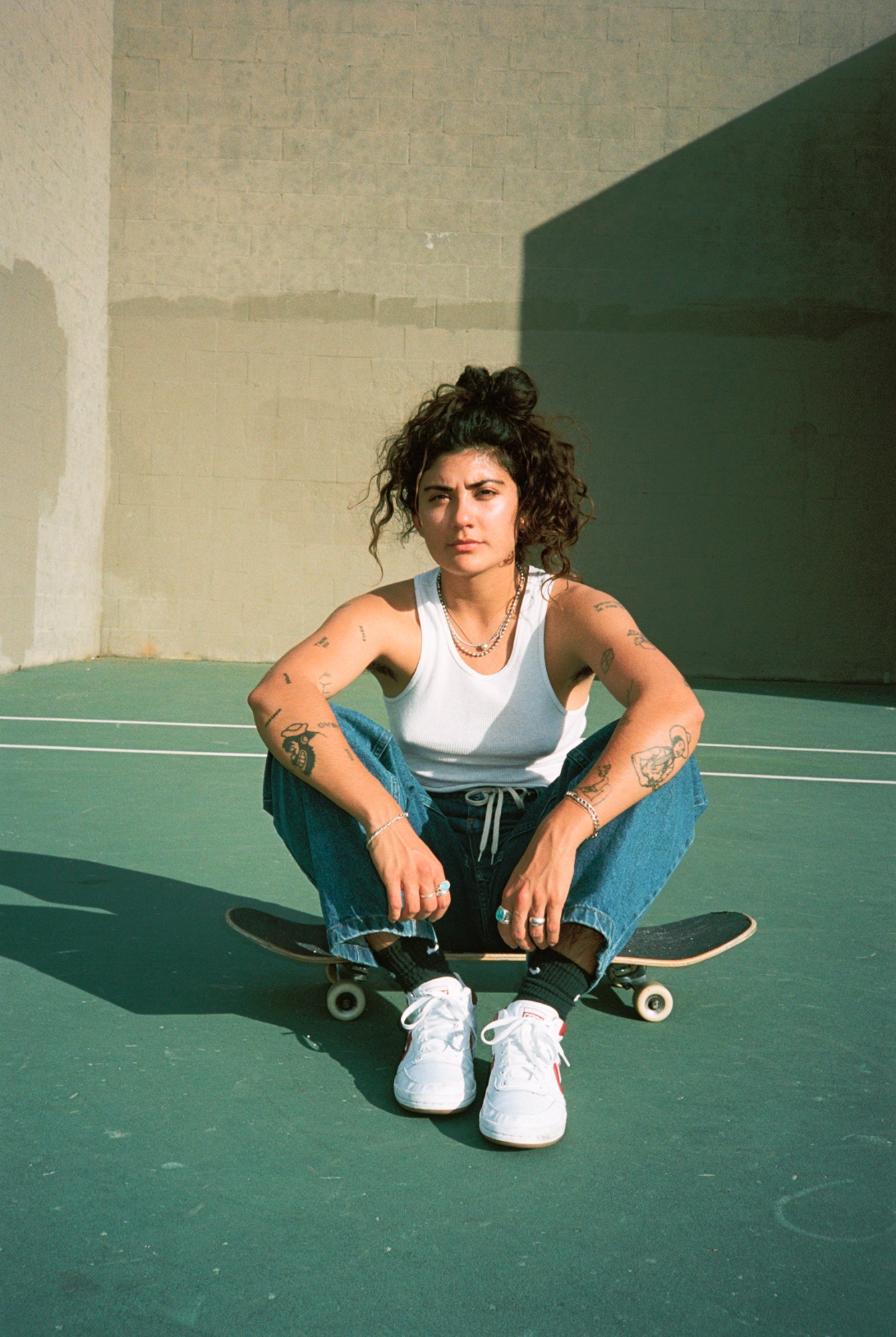 yaya chavez sitting on their skateboard at a park in los angeles