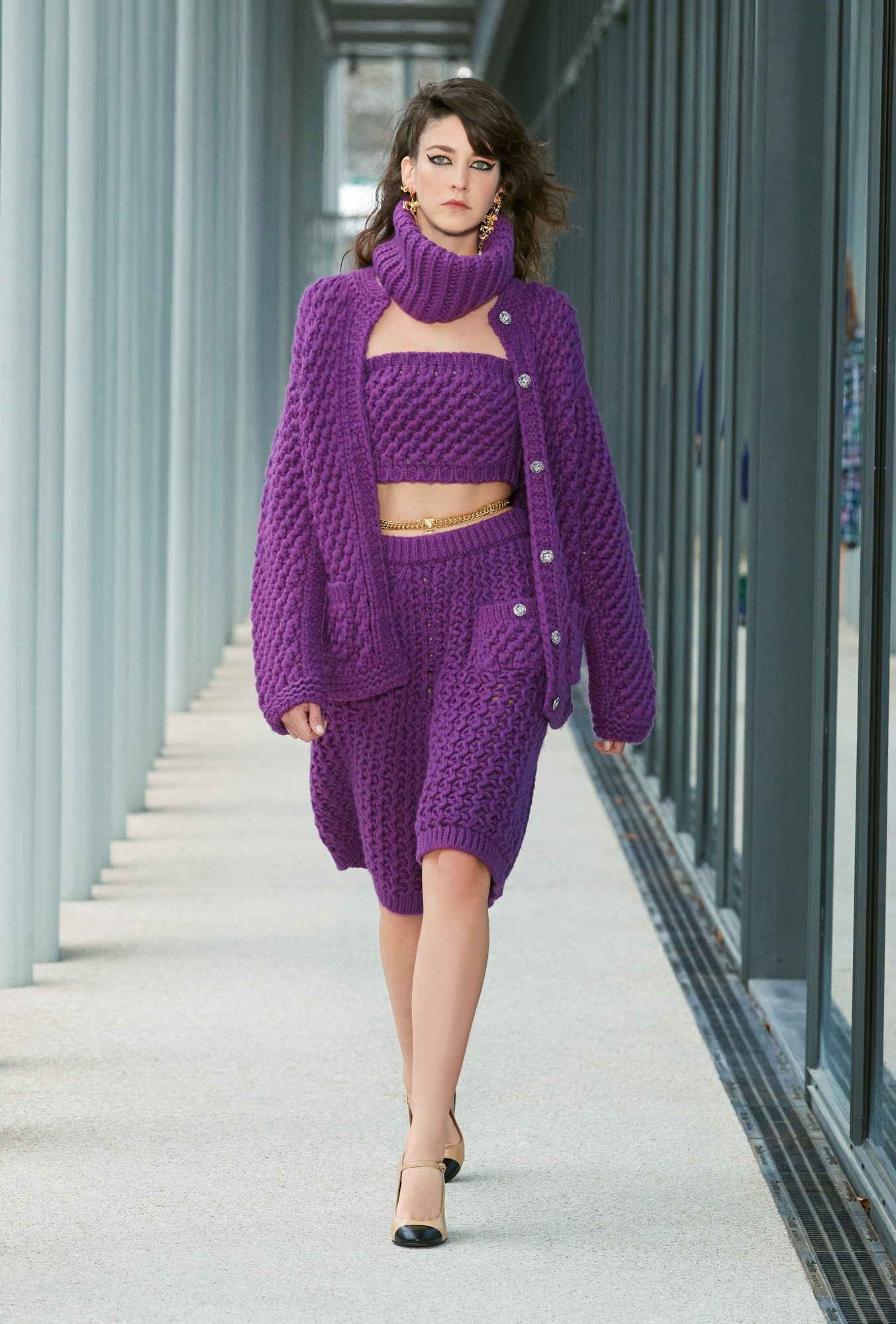 Model wears a matching four piece purple bobble knit look of a snood, bandeau top, cardigan and skirt.