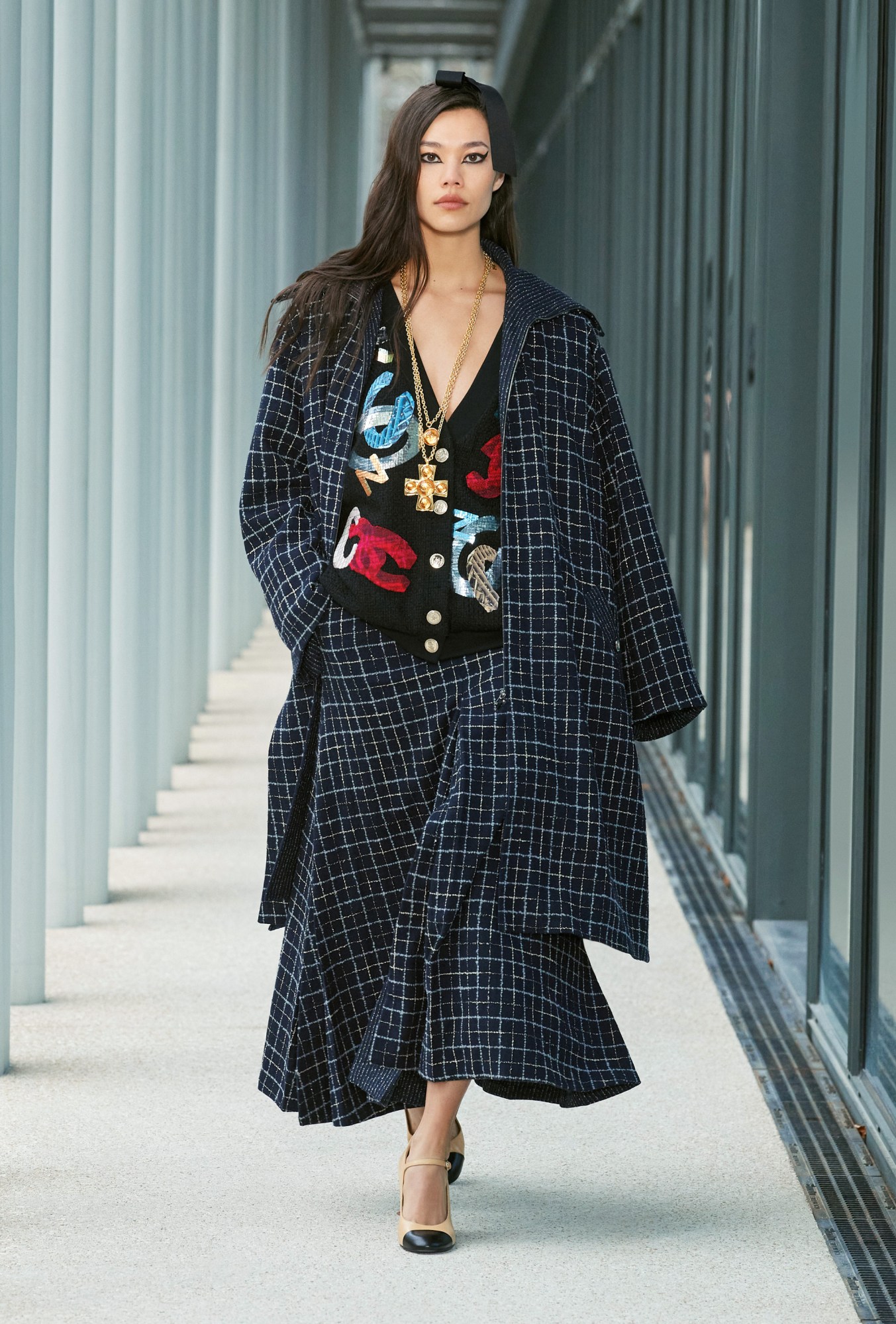 Model wears a two piece check maxi skirt and jacket with a black cardigan covered in patches.