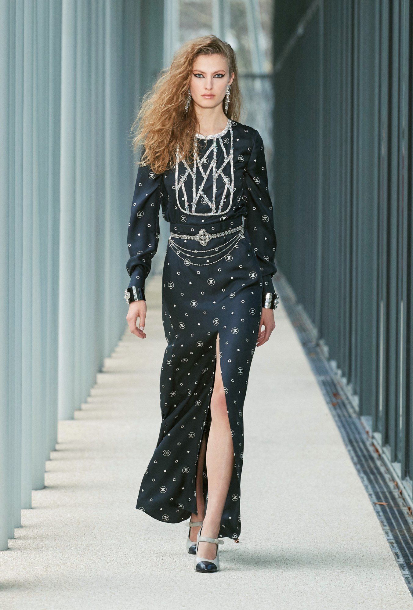 Model wears a monogram printed high slit dress with belts.