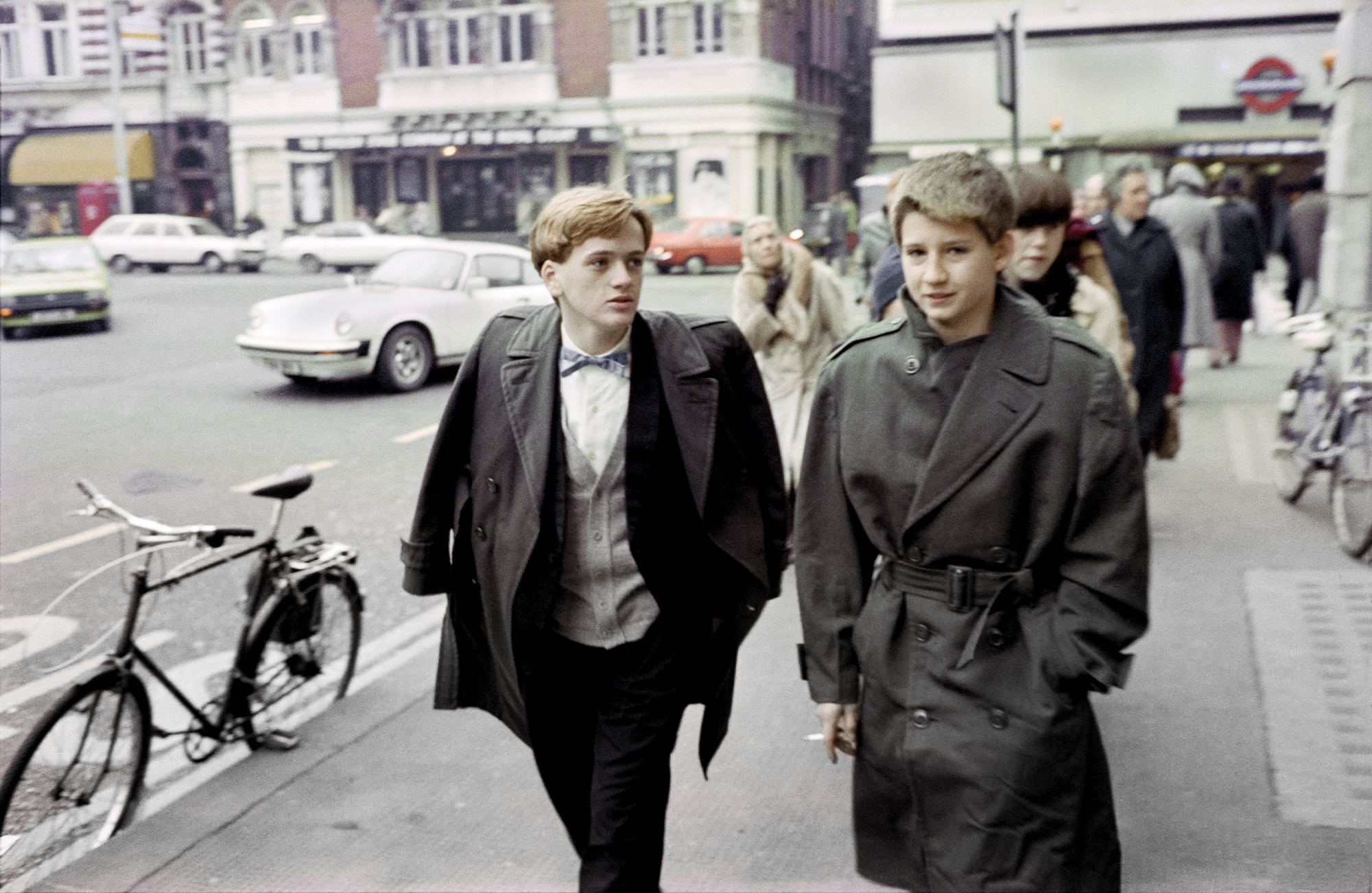 taken by sunil gupta in 80s london, two white boys dressed like businessmen walk down the street