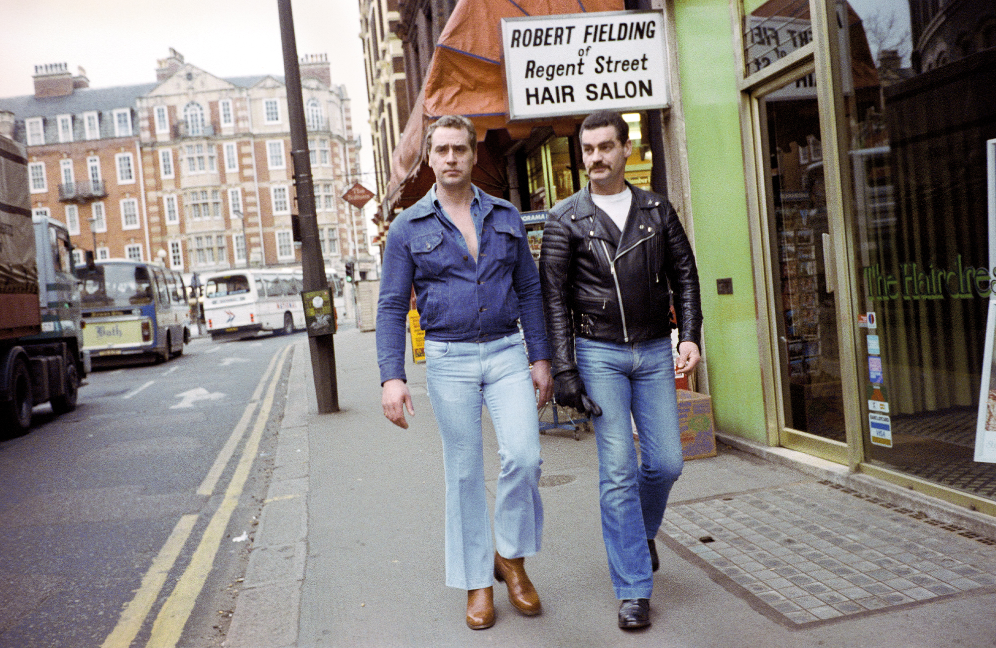 taken by sunil gupta in 80s london, two white men in flared jeans walk down the street