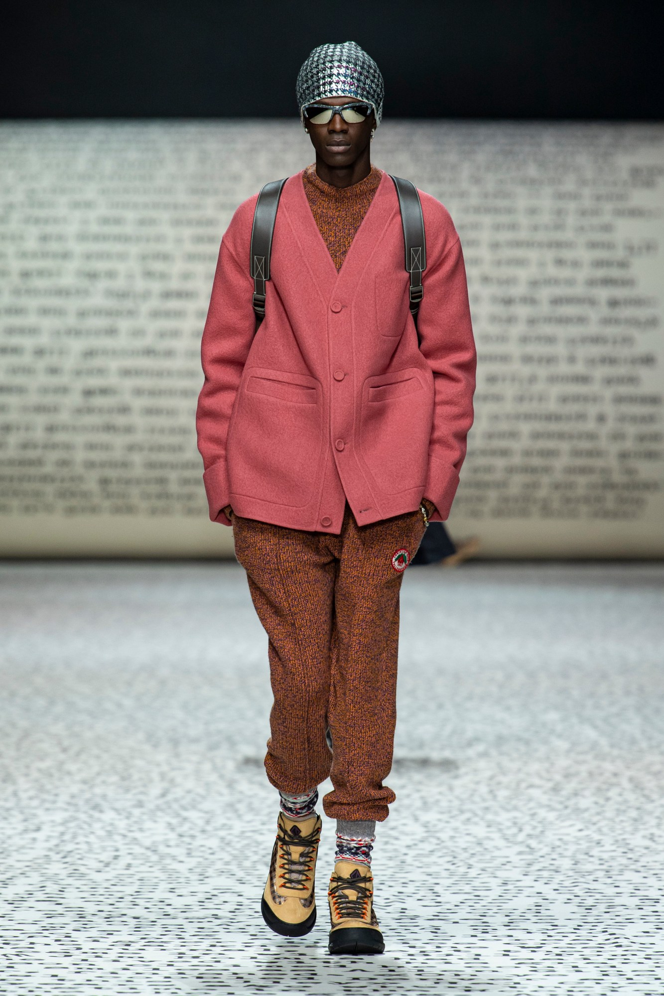 Model wears red joggers set with a red cardigan and cream boots.