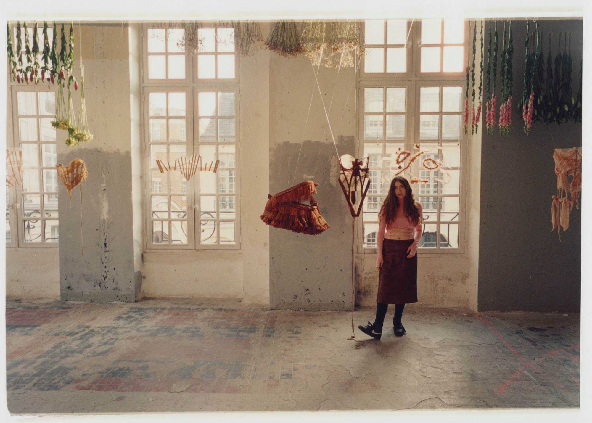 A photo of designer Michaela surrounded by suspended pieces of her work