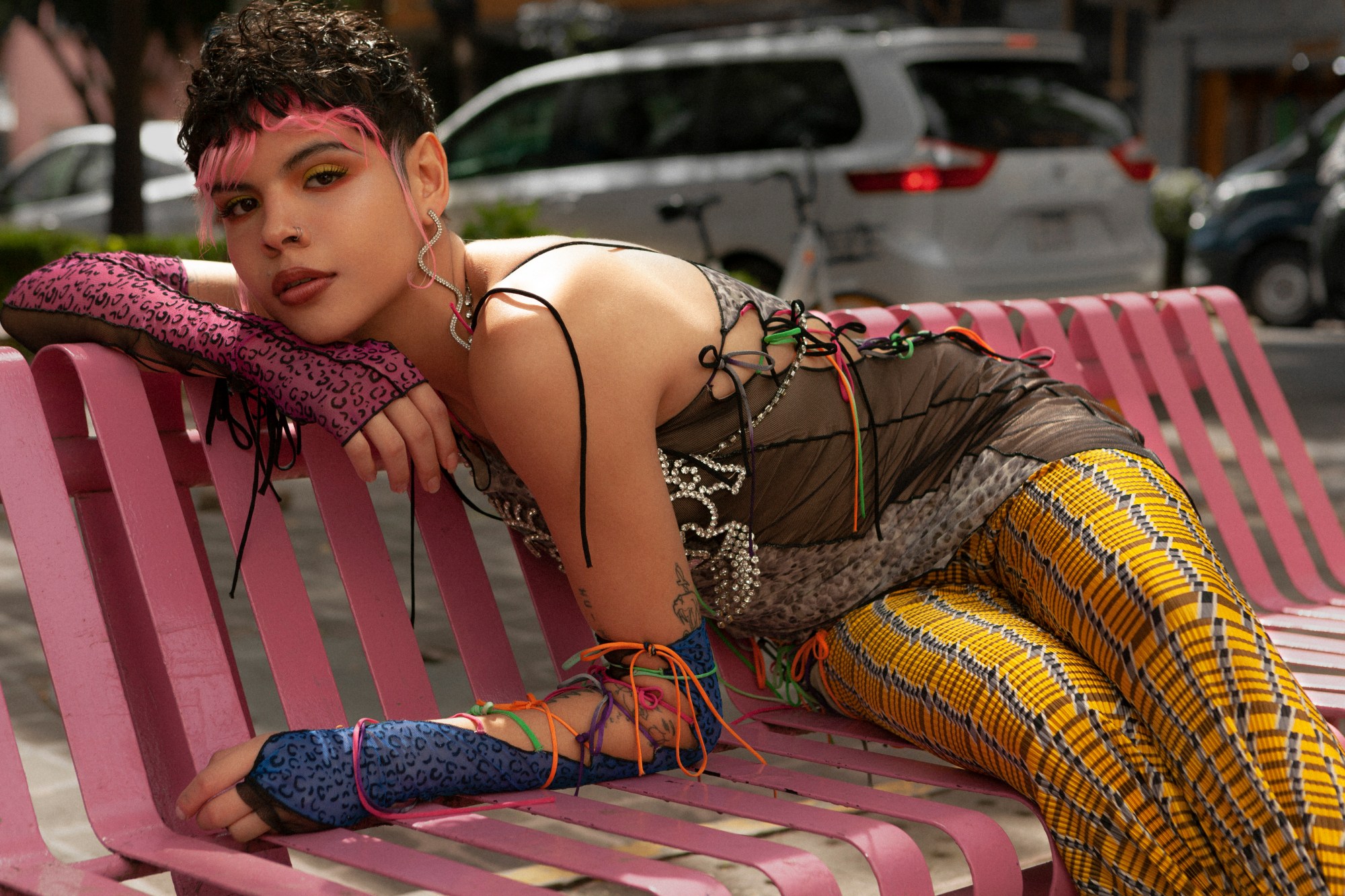 a portrait of melon rivas lying on a pink bench in mexico city