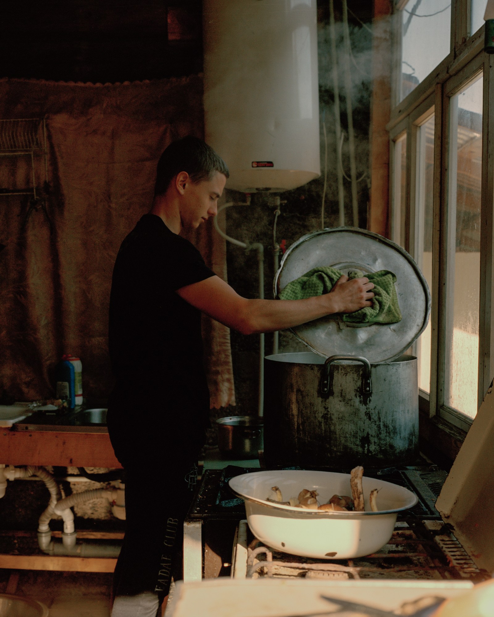 a man looking into a pot on a kitchen stove