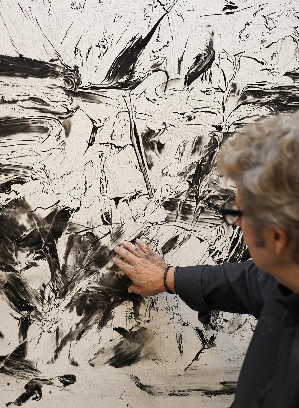 Robert Longo touches his art work.