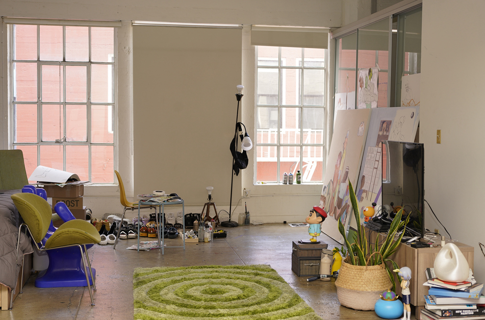 Bryant Giles work space with green chairs and rug, a white screen and art works against the wall.