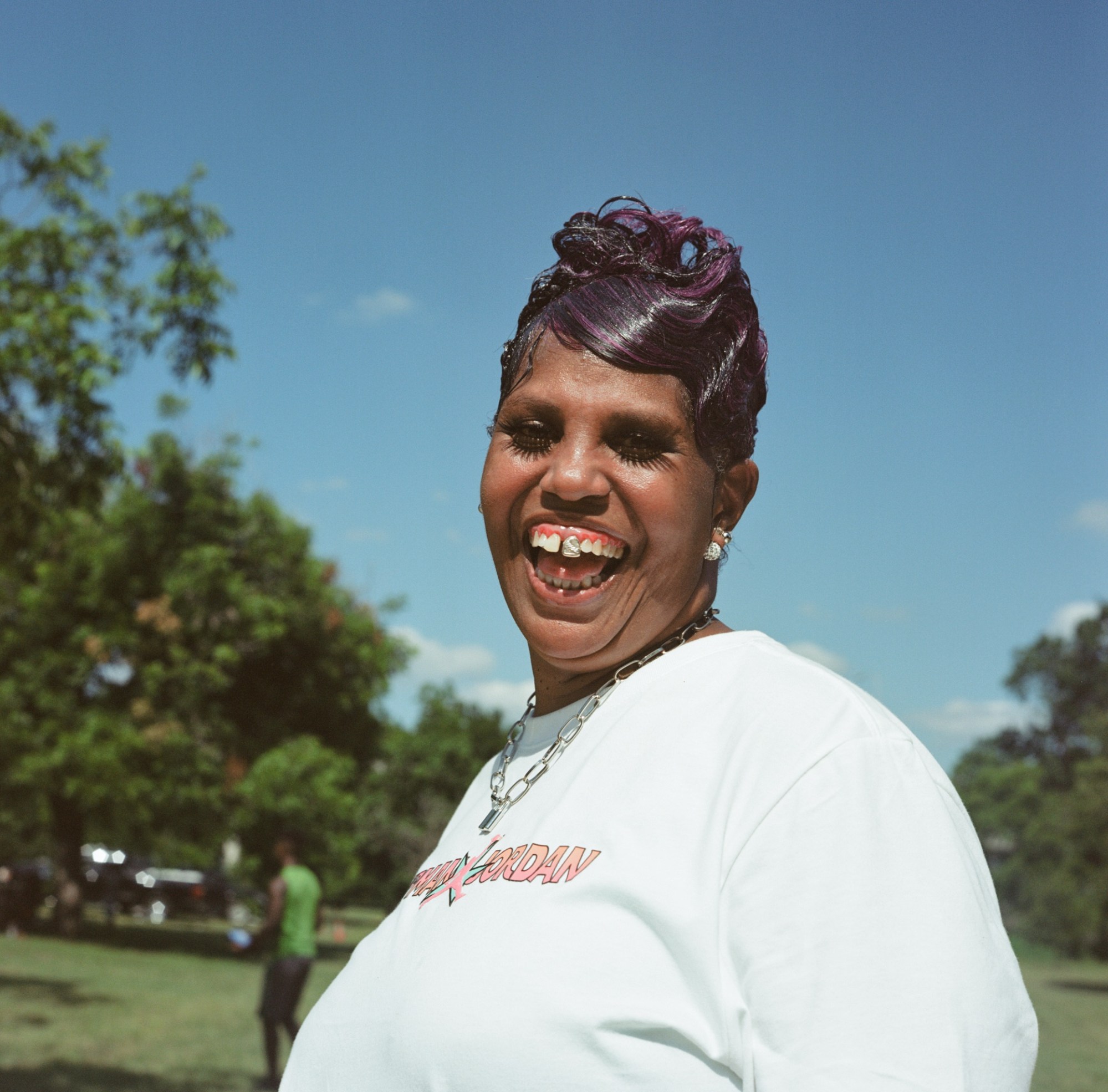 a woman with purple hair and a large tooth gem smiling at the camera by kennedi carter