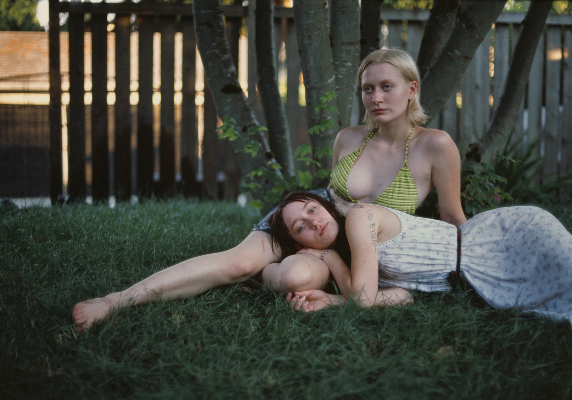 a girl in a green striped bikini and a girl in a dress lounging in the grass by kersti jan werdal