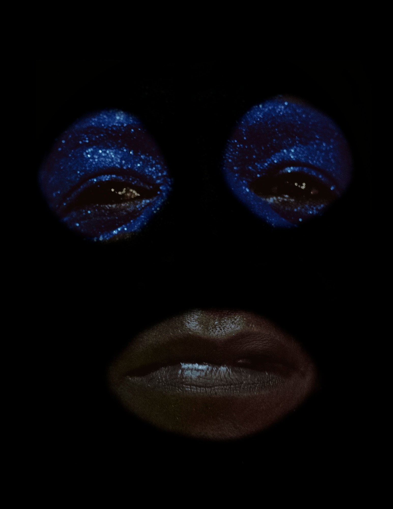 a carnival performer with sparkling blue eyeshadow wearing a black mask by ibrahem hasan