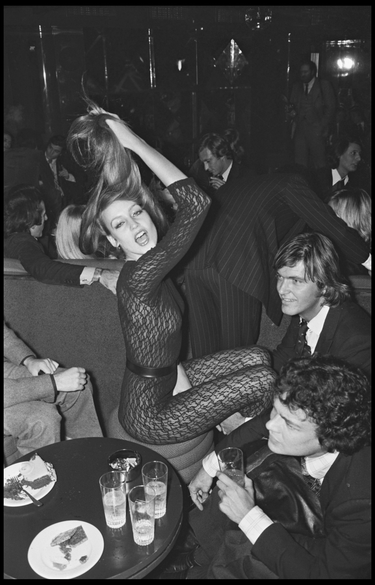 jerry hall holding her hair in.a lace catsuit and belt at a party in paris 1976