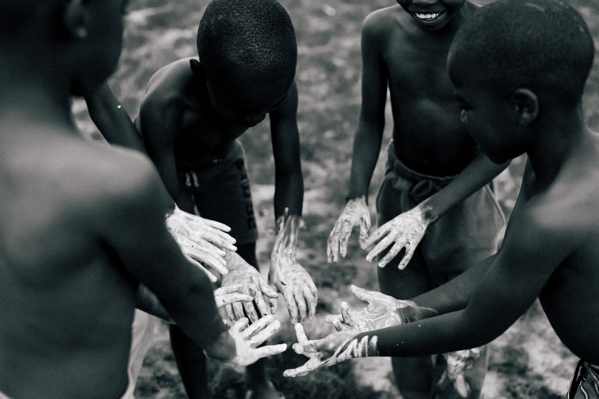 A group of young boys and girls stand in a circle with white paint on their hands.