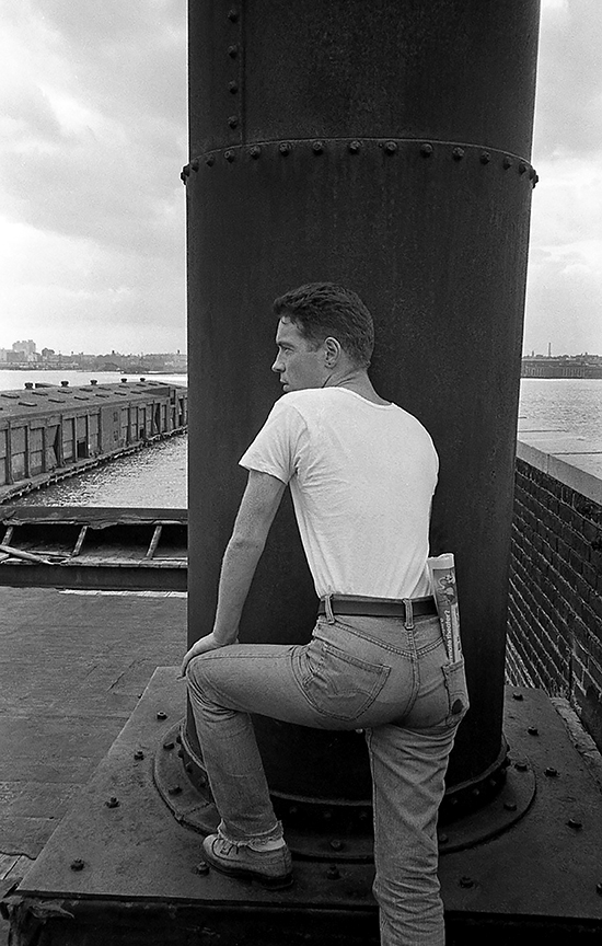 a man in tight levi jeans standing by the water at christopher street pier 1970s