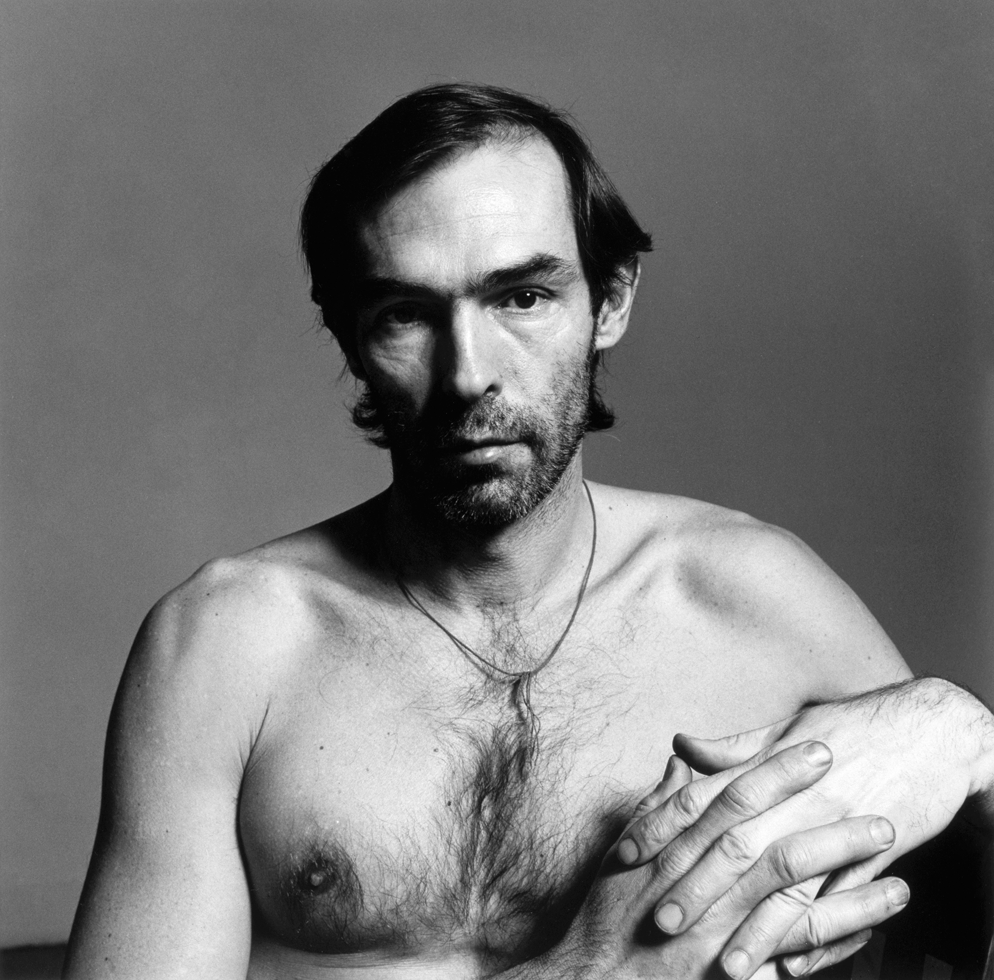 peter hujar sits and stares into the camera with no top on