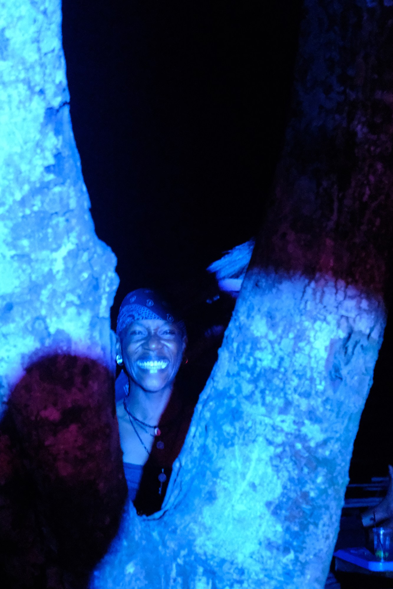 a person smiling between a tree wearing a paisley bandana