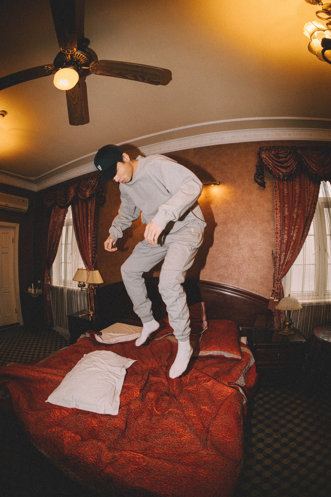 a model jumps on a hotel bed wearing UN GARCON CHARMANT AW22