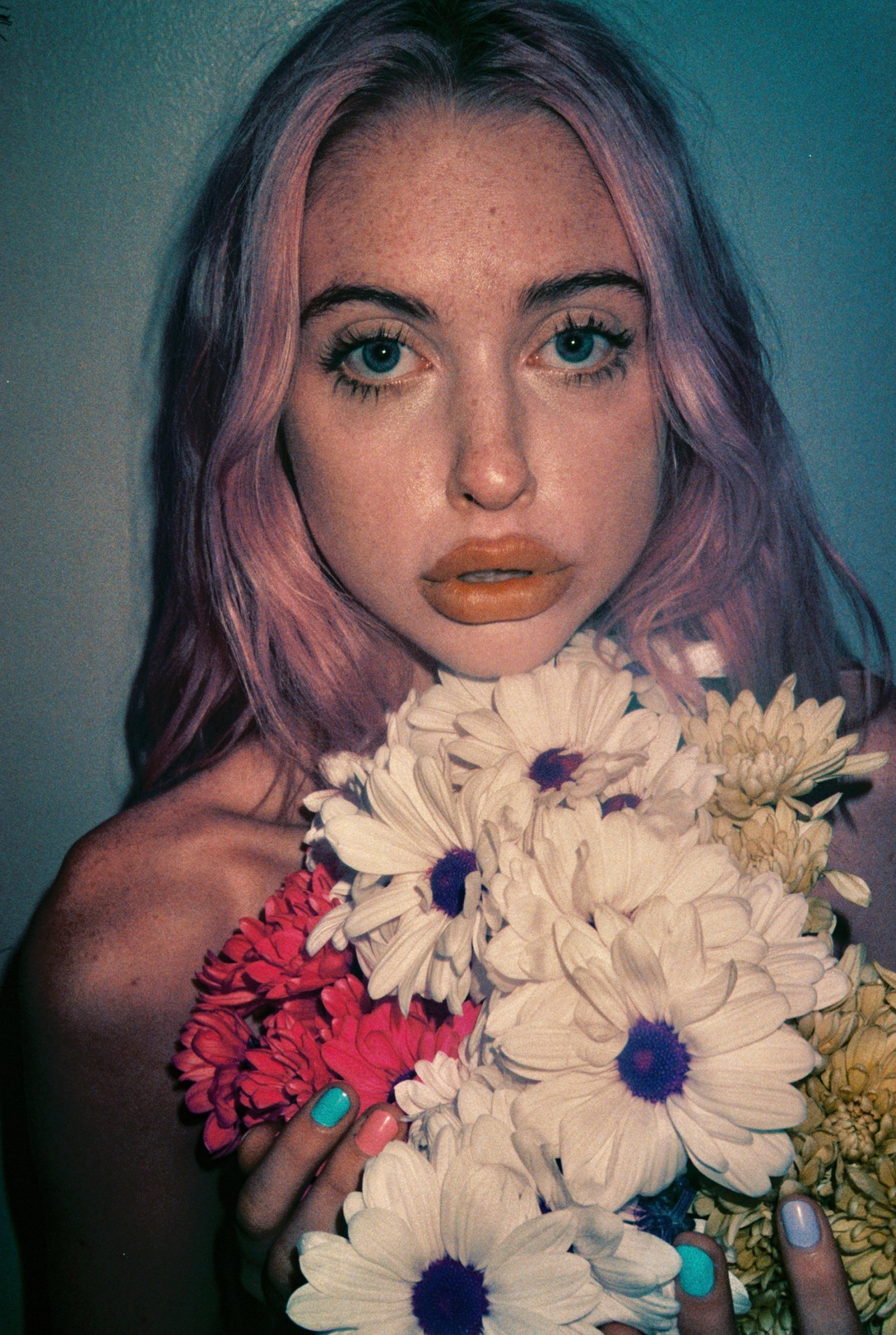 a close up of chloe cherry with pink hair holding flowers